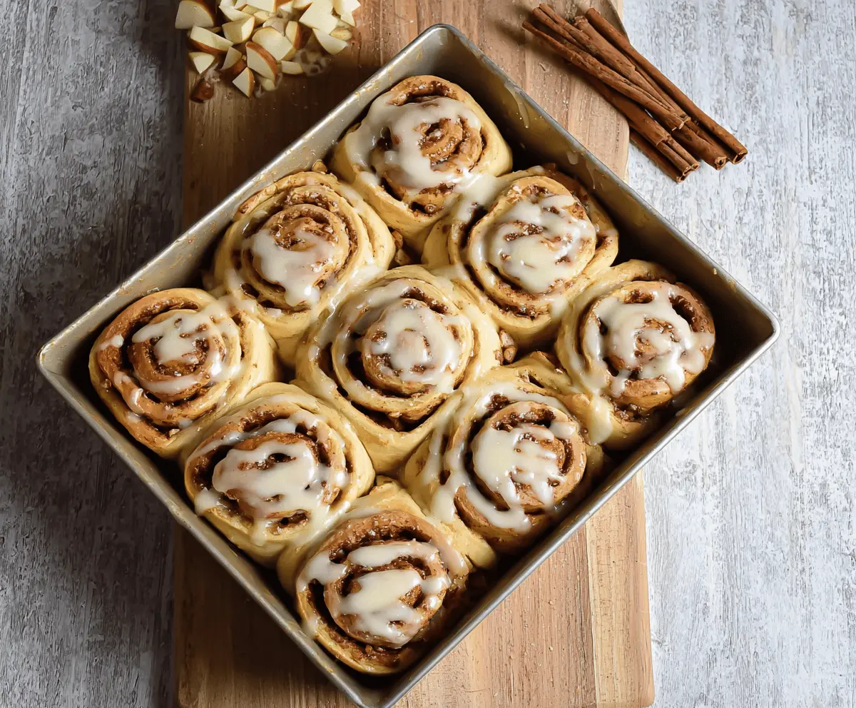Delicious homemade apple cinnamon rolls topped with icing, featuring warm cinnamon-spiced filling and fresh apple slices for a cozy breakfast treat.