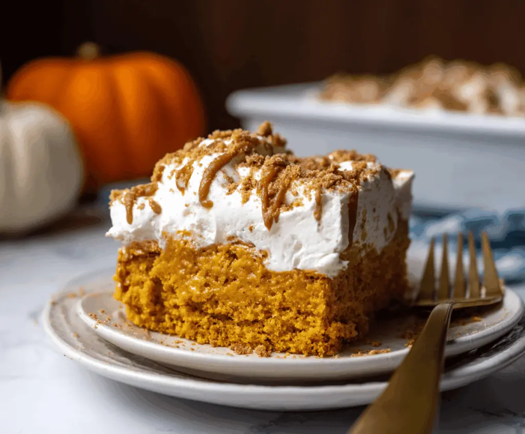 Delicious Pumpkin Poke Cake topped with whipped cream and cinnamon, perfect for fall desserts.