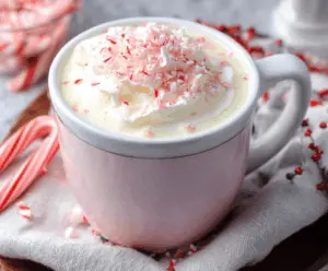 Creamy Crockpot Candy Cane White Hot Chocolate topped with whipped cream and crushed peppermint for a festive winter treat.
