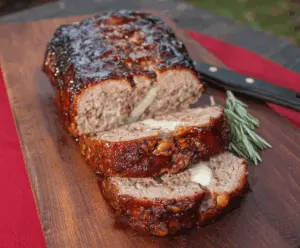 Delicious smoked meatloaf garnished with fresh herbs on a rustic platter.