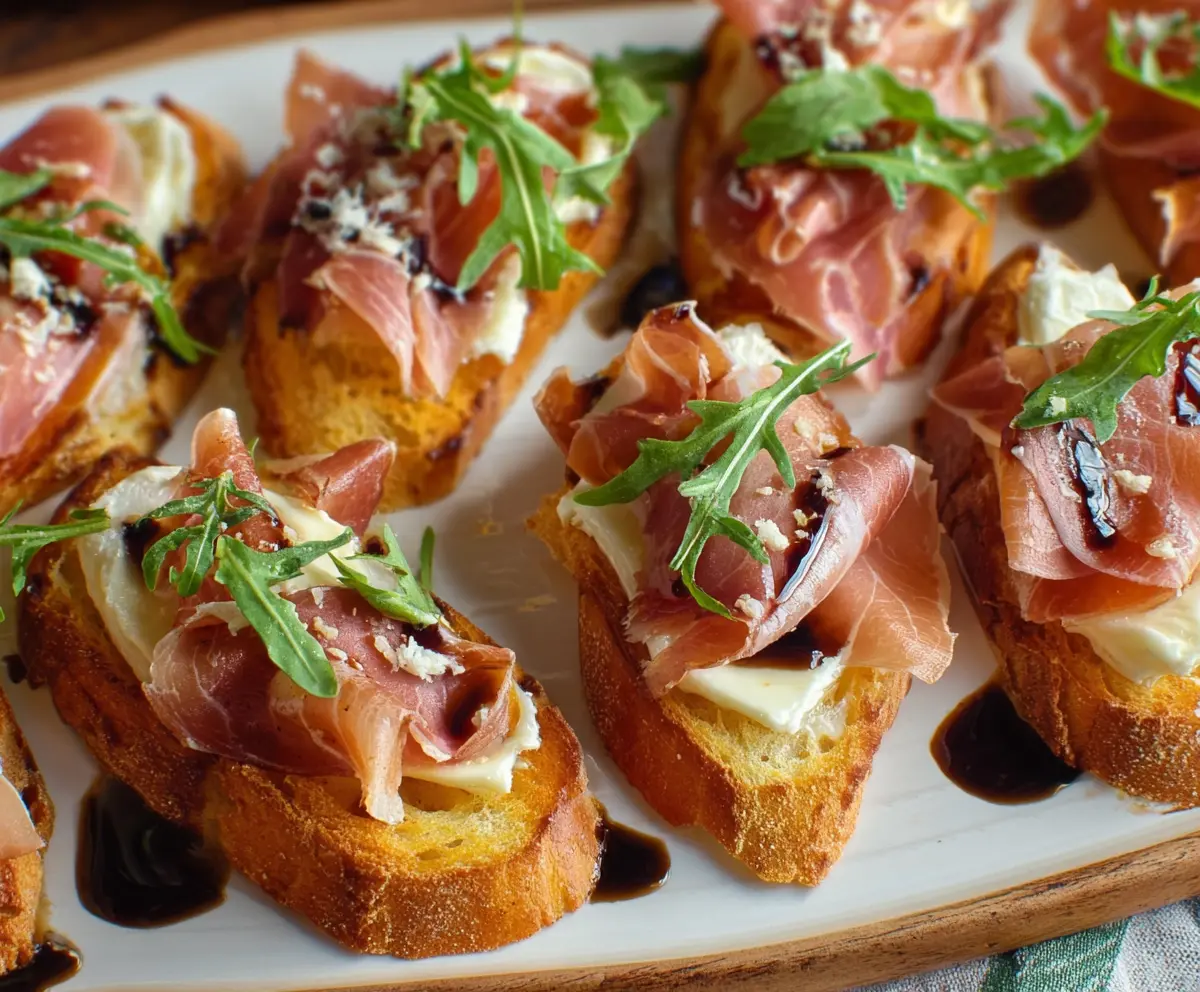 Delicious Brie and Prosciutto Crostini served on a rustic platter, showcasing creamy cheese and savory ham on toasted baguette slices.