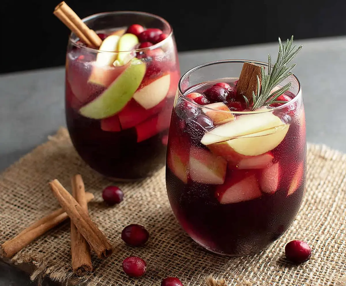 Refreshing Cranberry Apple Cider Sangria served in a glass with fresh cranberries and apple slices for a festive holiday look.