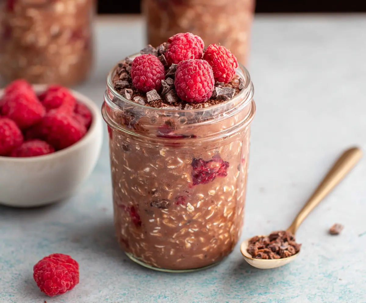 Delicious Chocolate Raspberry Overnight Oats topped with fresh raspberries and cocoa powder