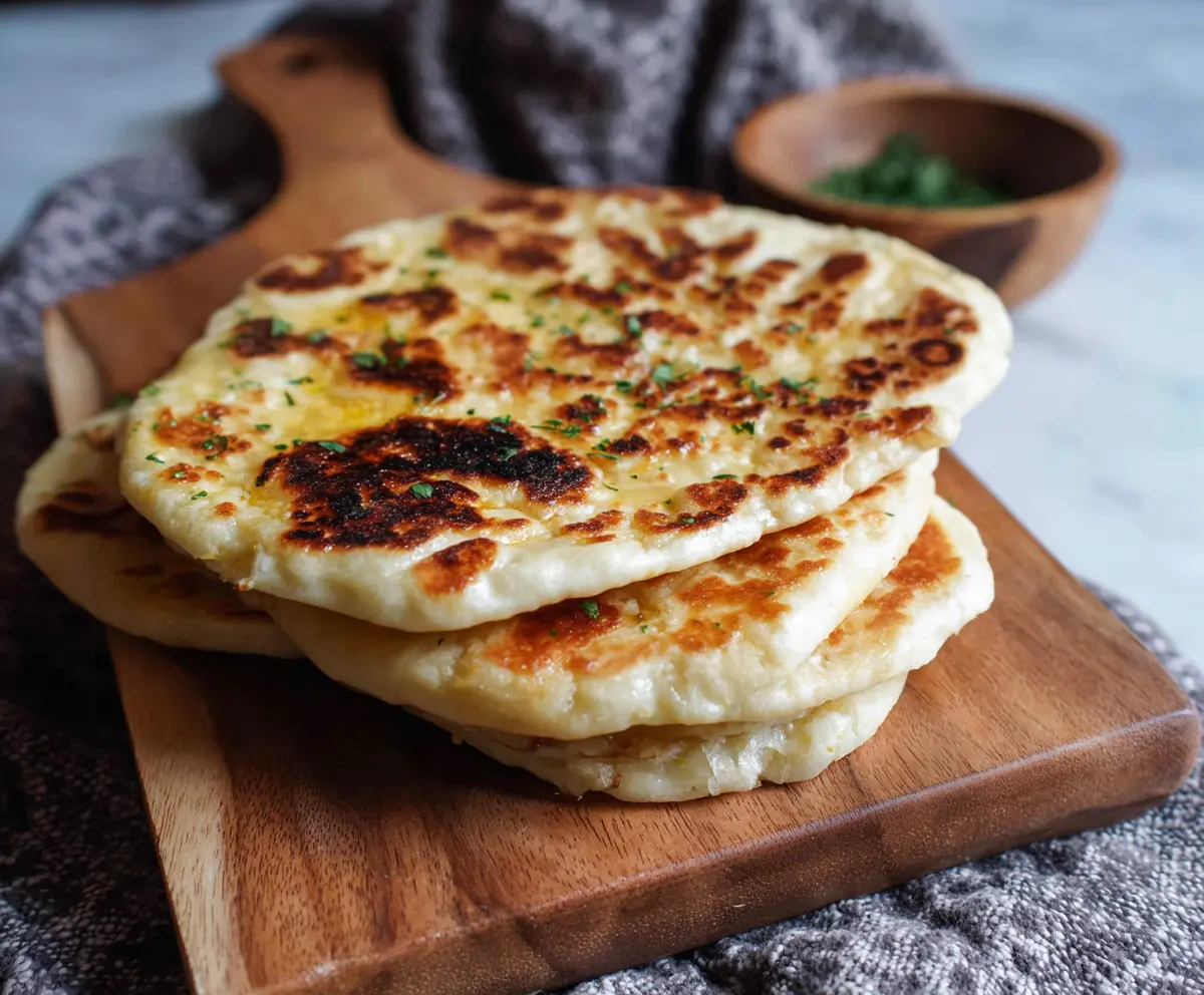Delicious sourdough discard naan bread on a wooden serving board ready to be enjoyed.