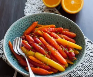 Delicious glazed carrots with orange and ginger garnished on a white plate.
