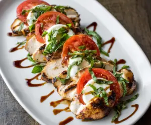 Delicious grilled chicken topped with fresh mozzarella, ripe tomatoes, and basil for a Caprese-inspired dish.
