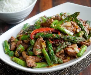 Healthy pork and asparagus stir fry served in a wok with colorful vegetables.