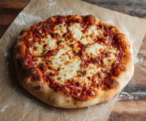 Close-up of a homemade sourdough pizza crust ready for toppings on a wooden surface.