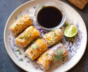 Crispy air fryer rice paper rolls filled with fresh vegetables and herbs on a white plate.