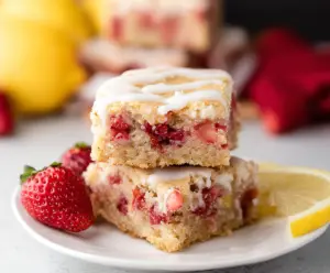 Delicious Lemon Strawberry Blondies on a plate with fresh strawberries and lemon slices.