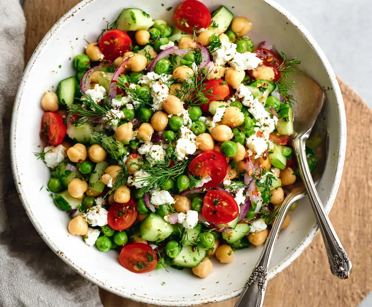 Fresh Mediterranean Pea Salad with cherry tomatoes, feta cheese, and herbs in a rustic bowl