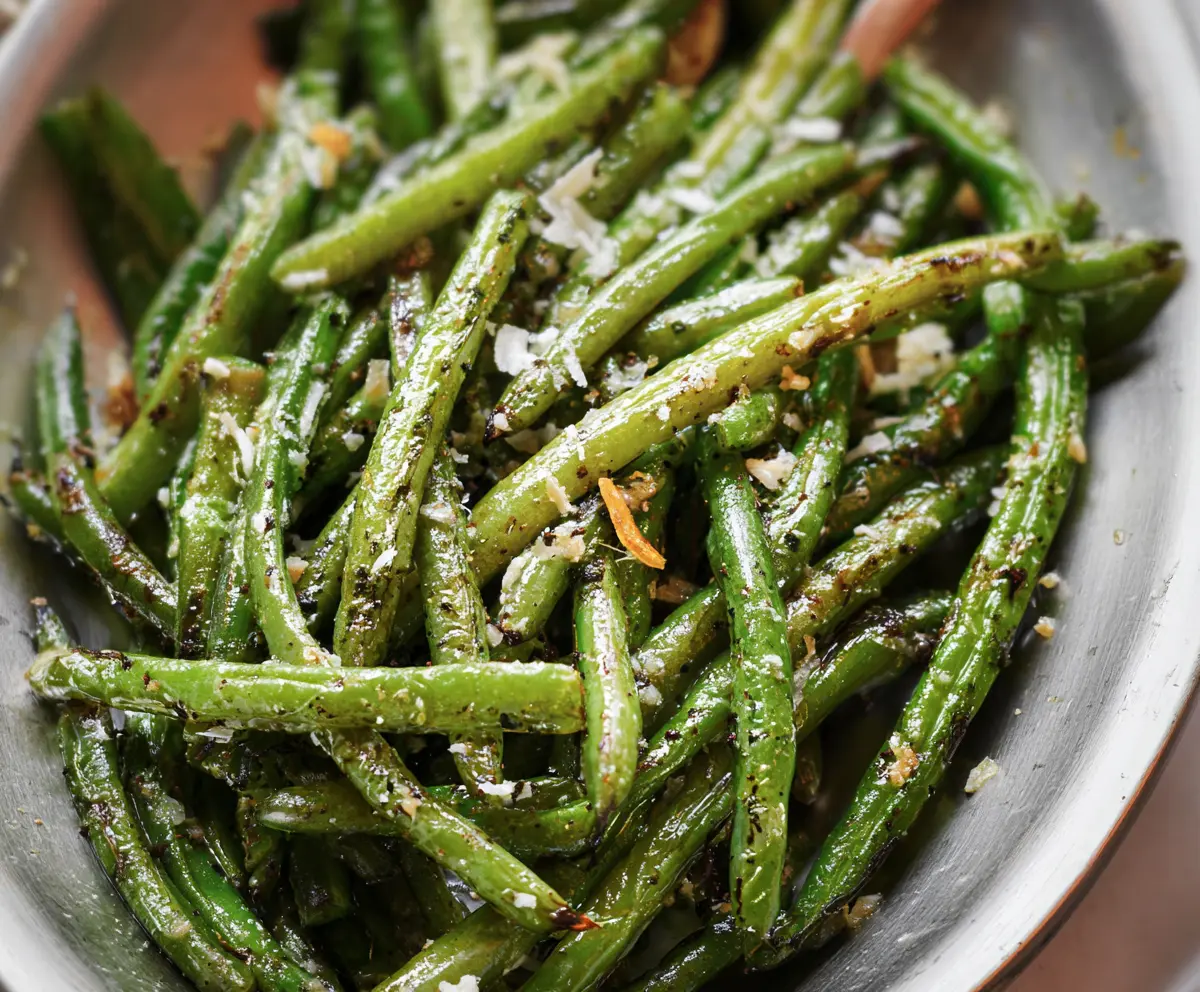 Delicious roasted green beans garnished with herbs on a white plate, perfect for a healthy side dish.
