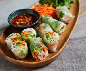 Fresh Thai vegetable spring rolls filled with colorful sliced vegetables and herbs, served with dipping sauce.